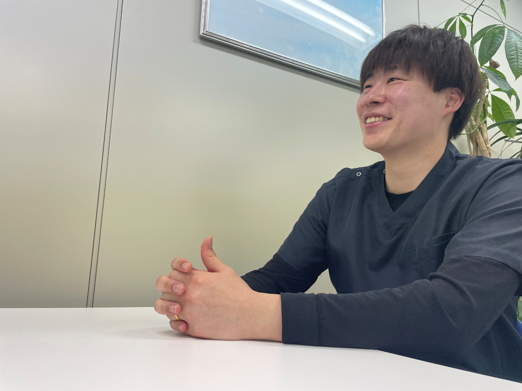 デスクで笑顔を見せる、まるっとけあの男性スタッフ